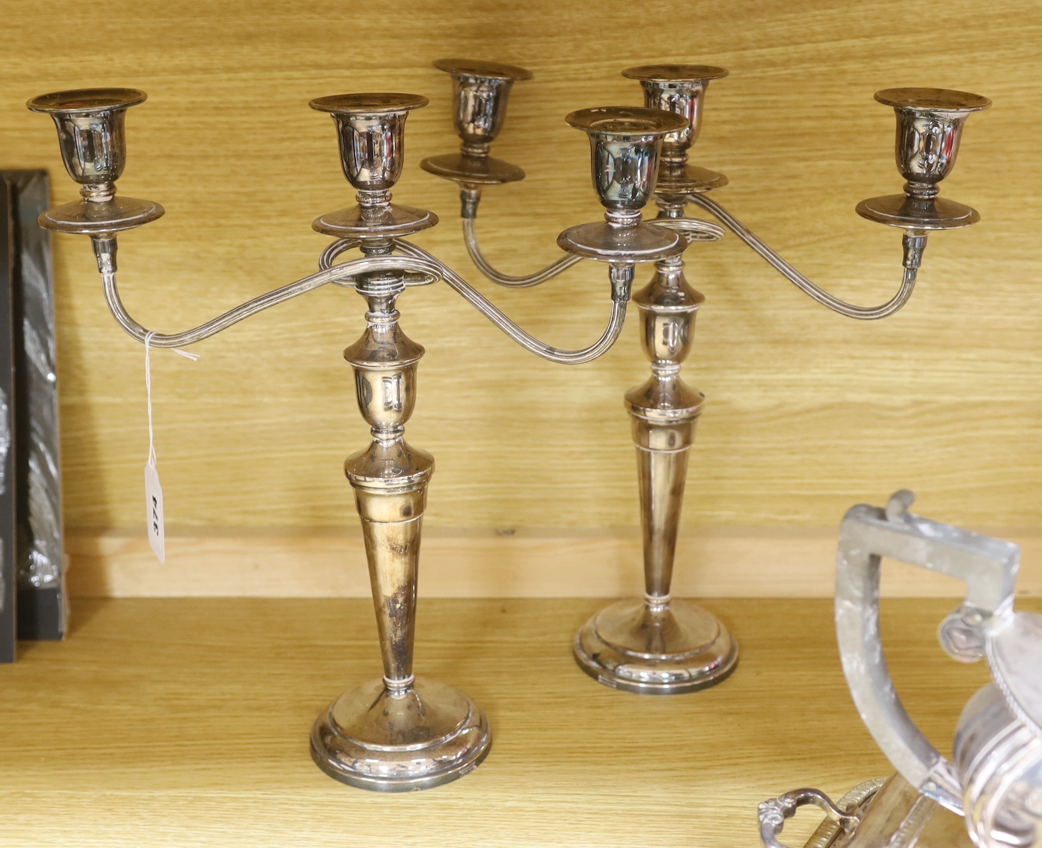 A group of silver plated items including a pair of three branched candlesticks, teapot, milk jug and sugar bowl, the largest 36cm high